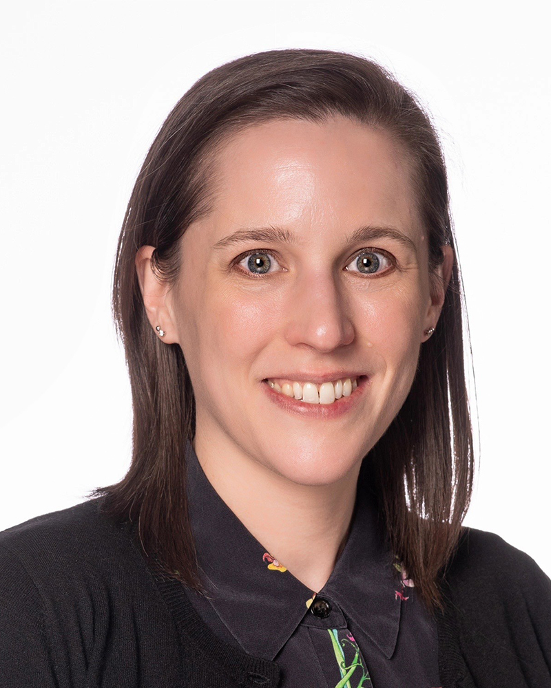 A headshot of Bernadette Perchalski wearing a black collared shirt with a white background. 