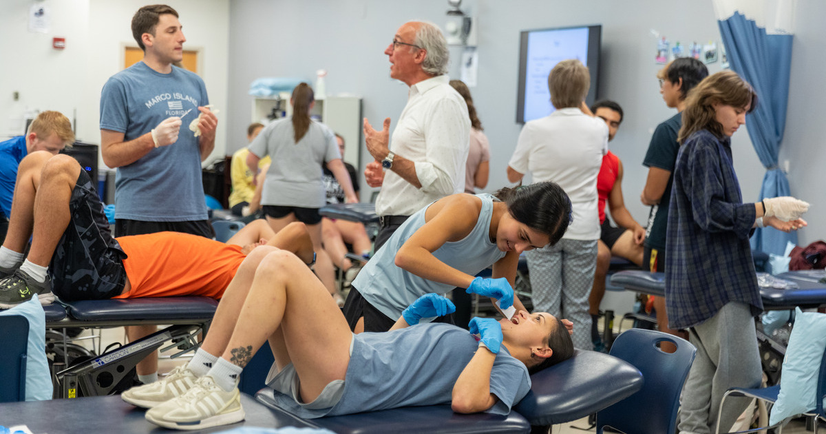 Physical therapy students are instructed in conducting basic evaluations techniques. Here, some students are lying down while others are standing. 