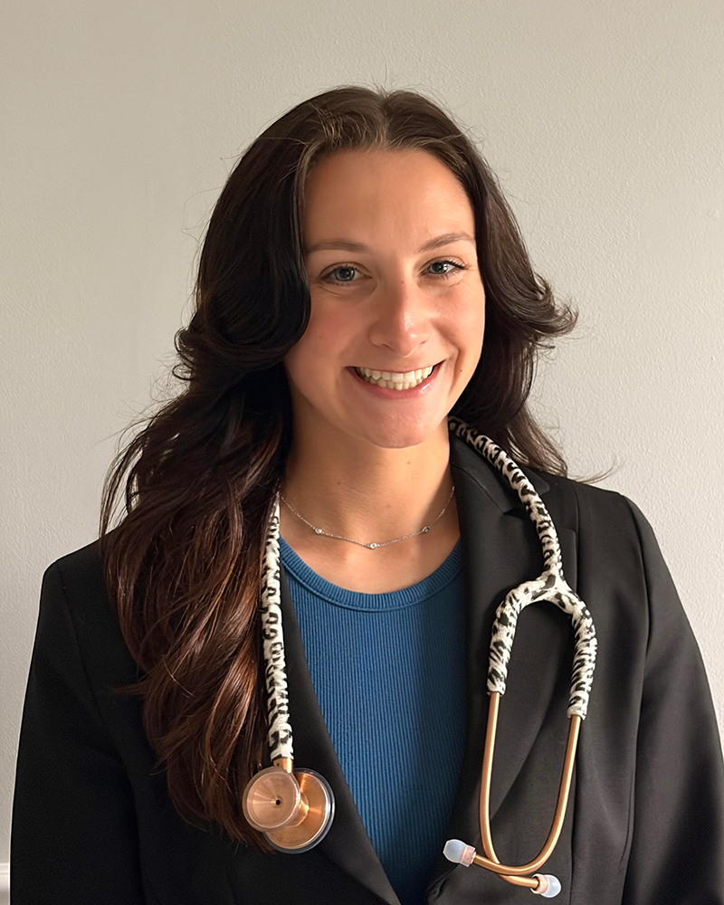 A headshot of Rachel Thomas, a senior nursing major, wearing a black jacket and a blue shirt with a stethoscope around her neck. 