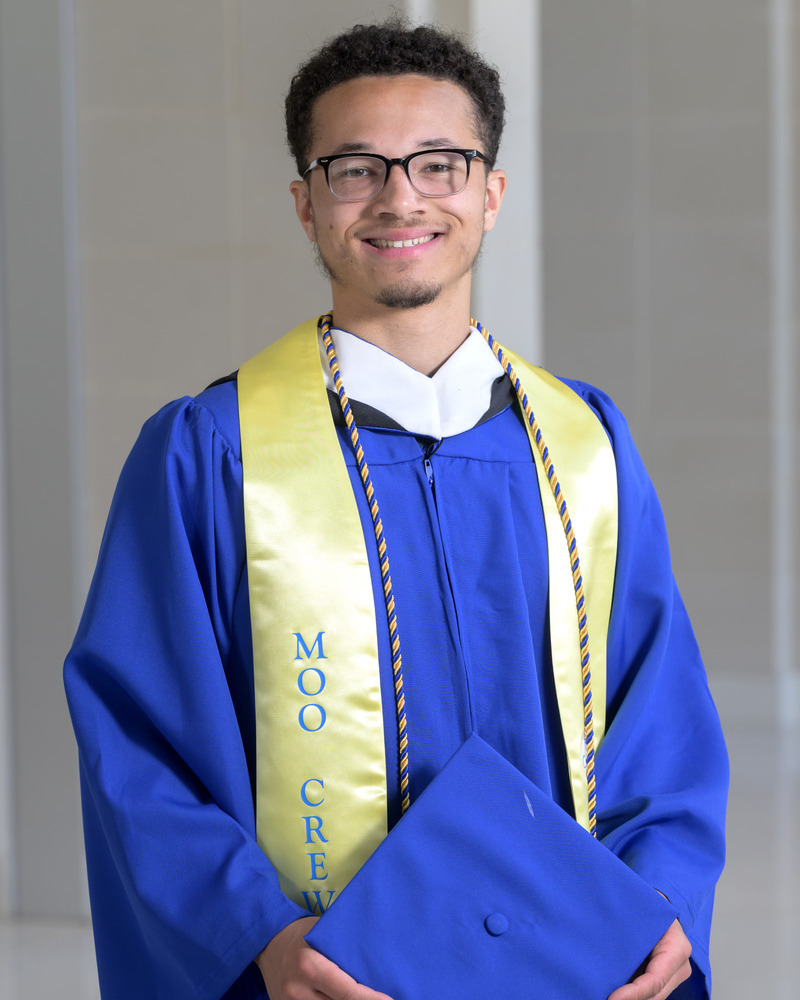 Senior Alonzo Walker wears his official UD Commencement regalia whole holding his cap.