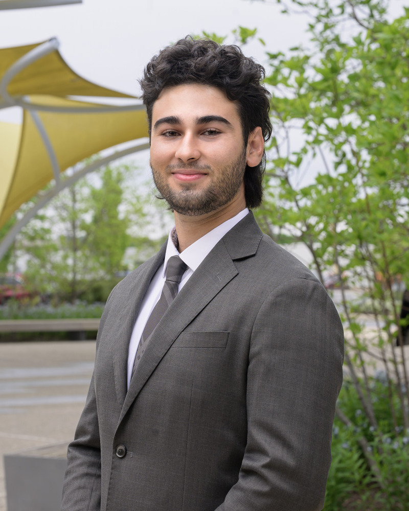 Headshot of Kyle Tubian standing to the side.. The senior kinesiology major wearing a gray-brown suit and tie.