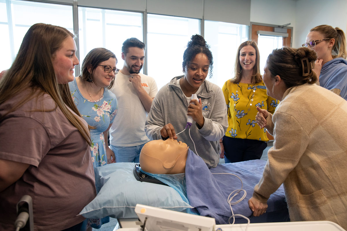 A group of students observe an endoscope simulation on maneuqins