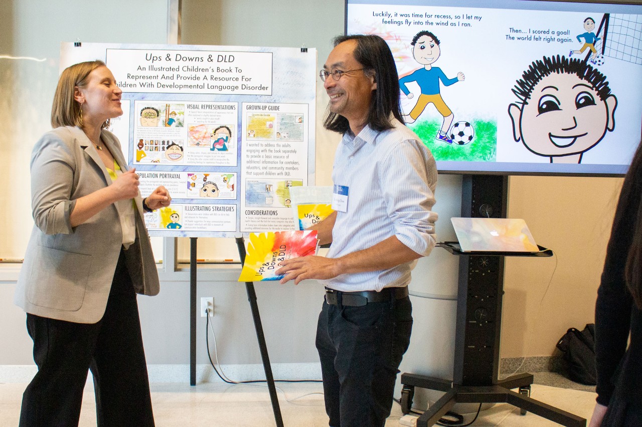 A graduate student presenting a poster and interacting with a faculty member