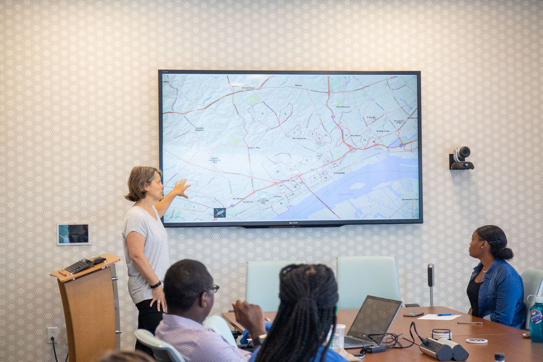 Jennifer Horney presenting to a group, pointing to a screen displaying a map