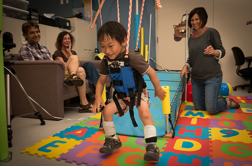 Tracy Stoner, physical therapist works with Xander in the baby mobility lab in the harness system. 