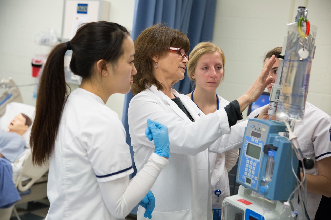 Nursing professor and students working with an IV machine