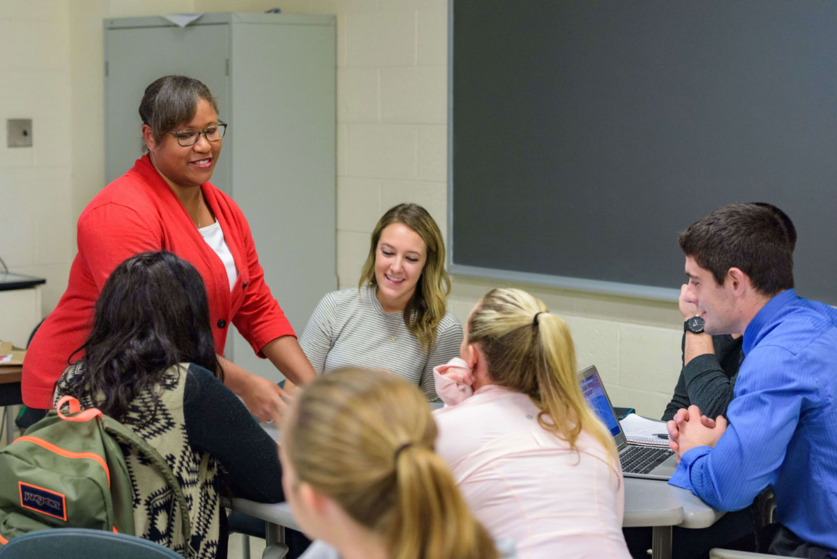 A group of individuals talking in a classroom. 