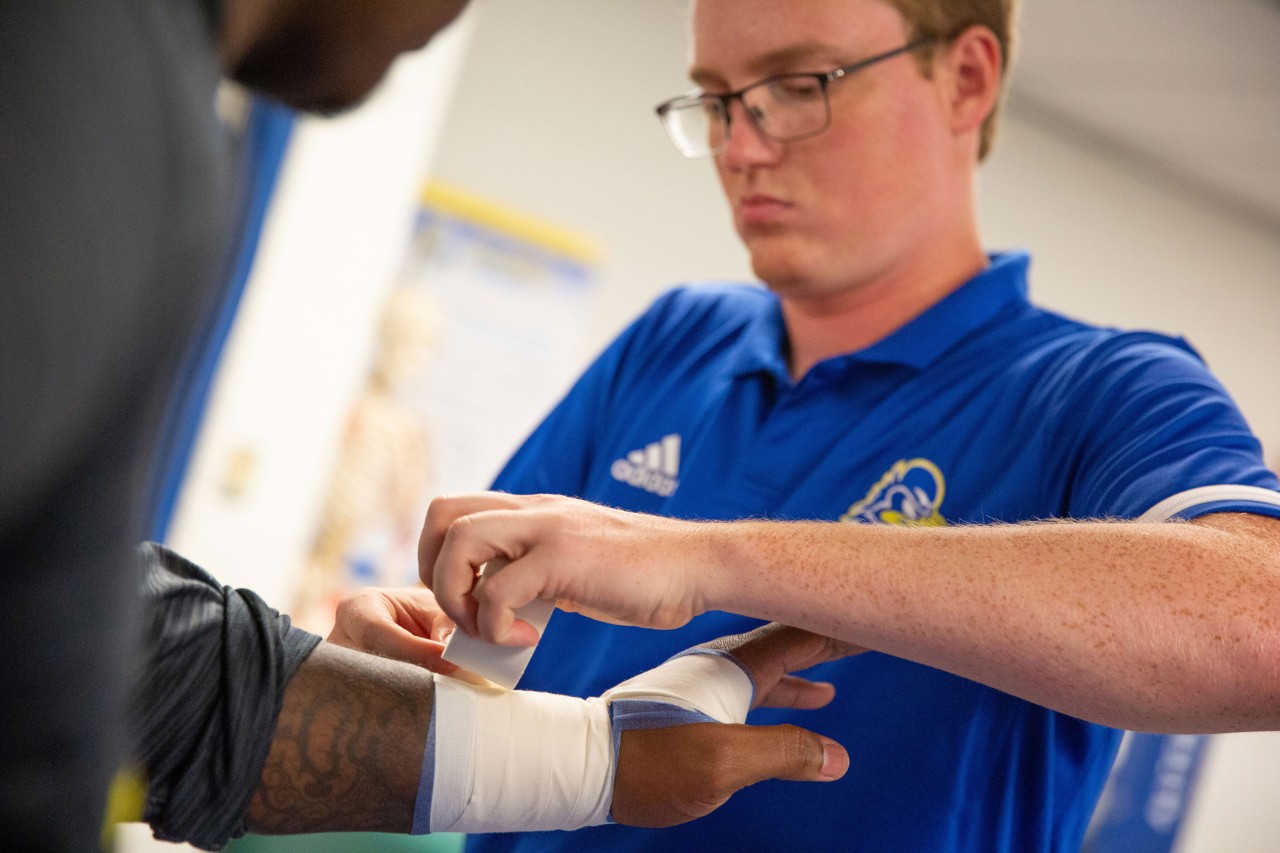 Student wrapping a wrist with medical tape