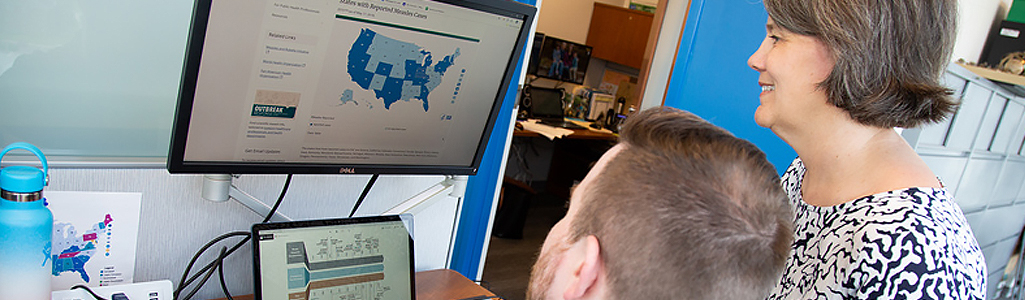 A professor and student review data mapping on a computer screen.