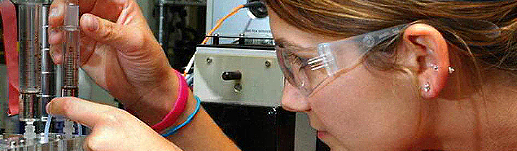 GradCollege-ChemistryBiochemistry Close up of a student with goggles doing a chemistry experiment.