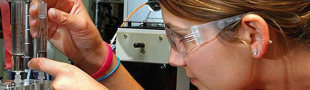 Close up of a student with goggles doing a chemistry experiment.