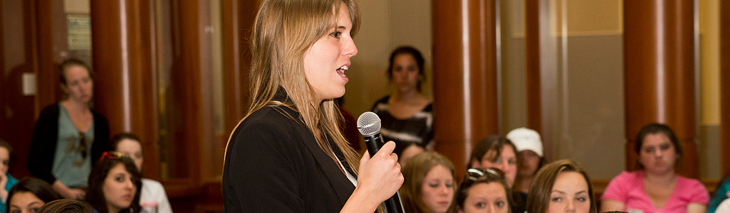 A student speaks into a microphone at a workshop.