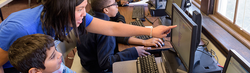 Education Teacher helping an elementary school student on computer