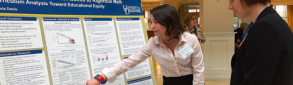 A graduate student explains her poster presentation at a conference.