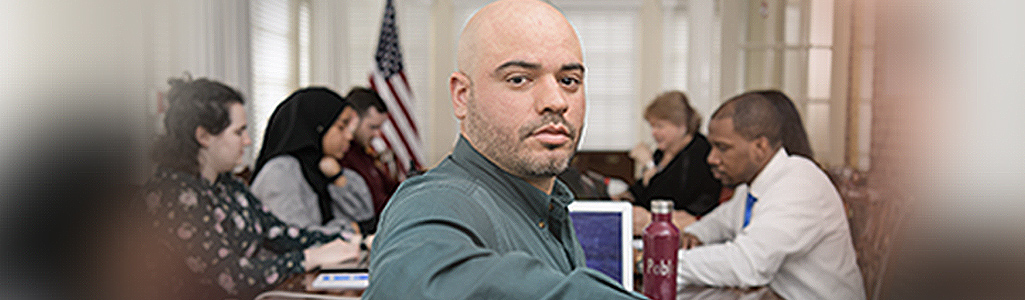 Environmental Science and Management A man facing the camera during a meeting with six others.