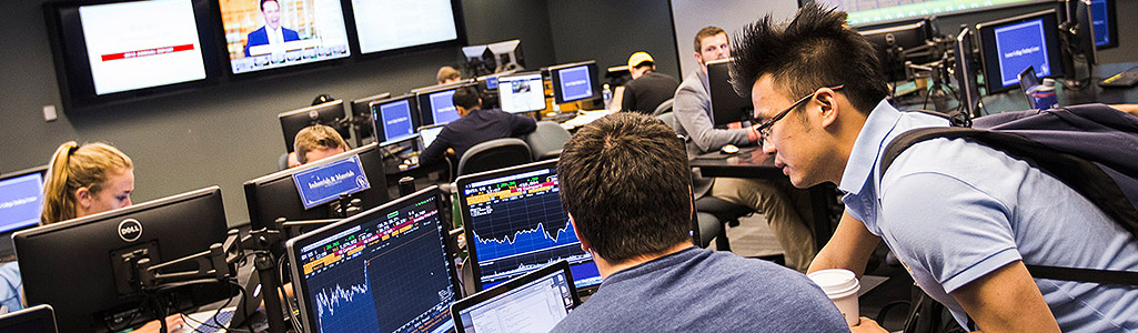 Finance Two students looking at finance data on a computer screen in a computer lab.