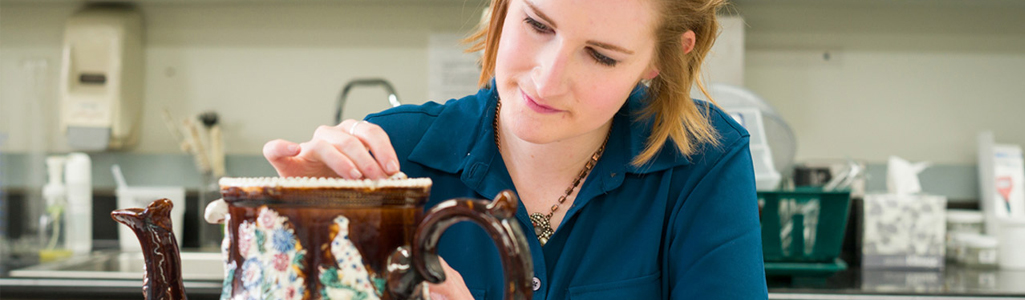Fine Arts Close up view of a female art student working on a piece of pottery.