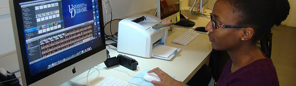 A female student sits at a desk as she works on a computer.