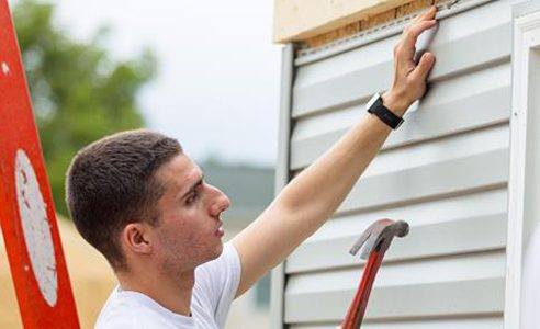 Men hammering nails into side of house.