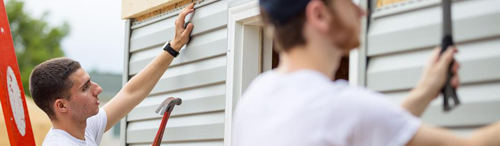 Men hammering nails into side of house.
