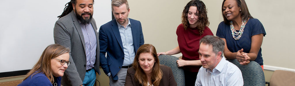 Group of professors reviewing something on a laptop.