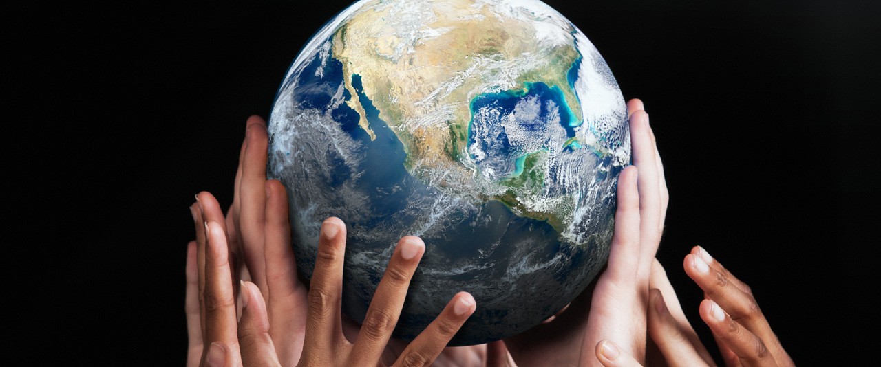 Hands holding up a globe against a black background.