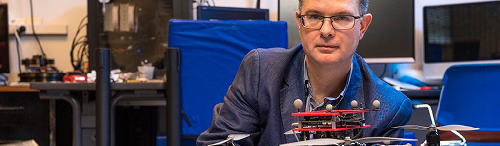 Professor in Electrical and Computer Engineering with a robot on table.