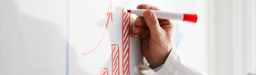 Hand drawing a bar chart on a white board.