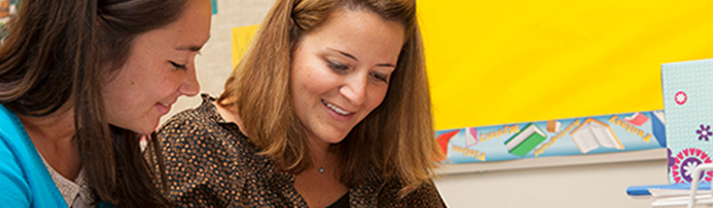 A teacher mentors a student in the classroom.