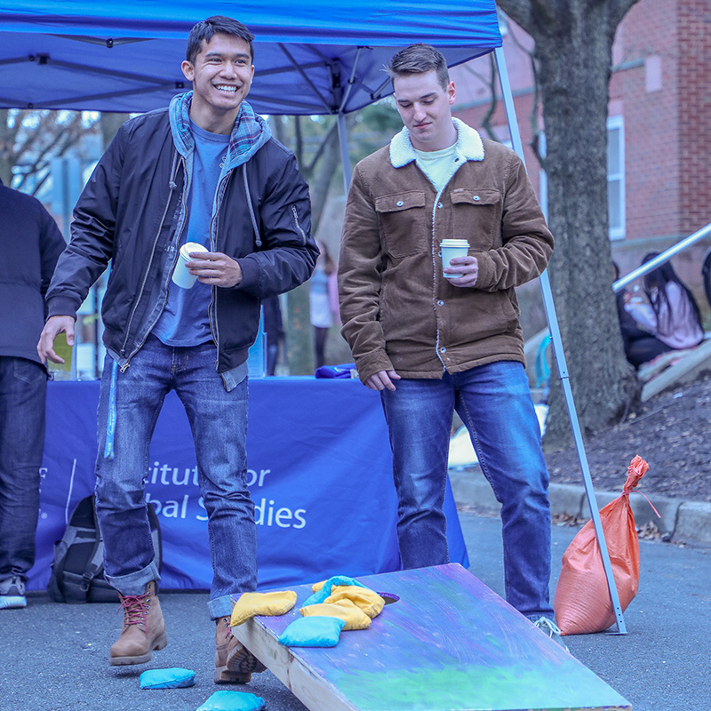 Two students play a game of cornhole at an iHouse block party