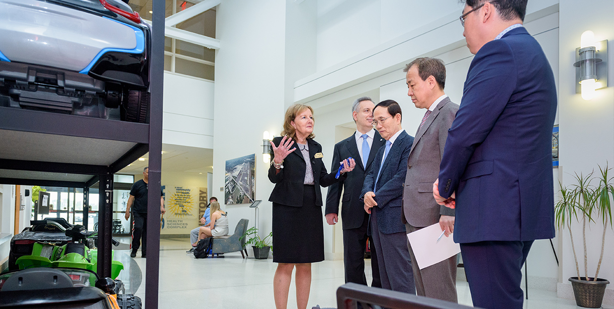 A delegation stands learning more about the STAR Campus and Go-Baby-Go Program