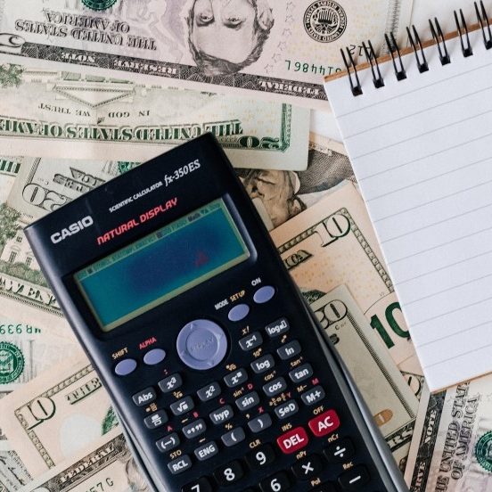 A calculator lying over a pile of American currency.