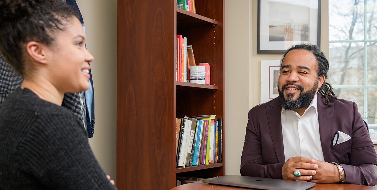 A UD professor speaks with a student in a University office.