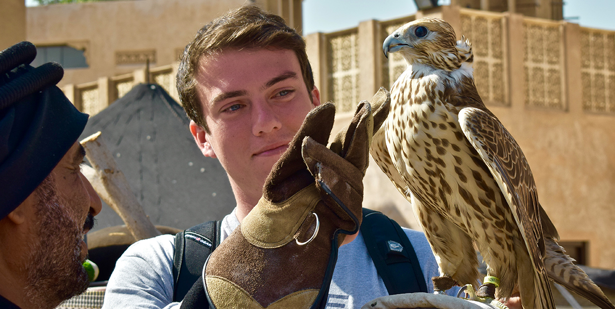 A student listens to a hawk trainer holding a bird. 