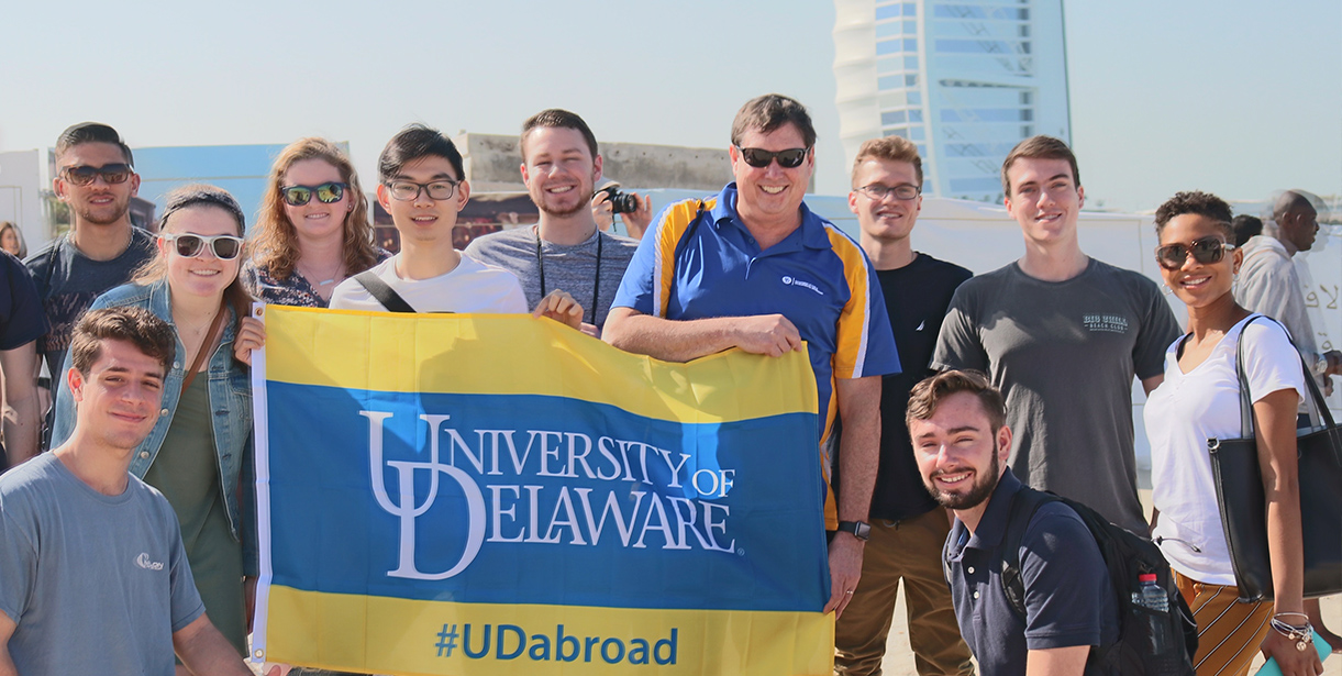 Study Abroad students and their faculty director stand with a #UDAbroad flag in Dubai
