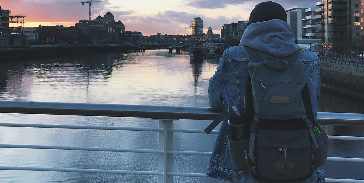 A Study Abroad student stands looking over an Irish cityscape and waterway. 