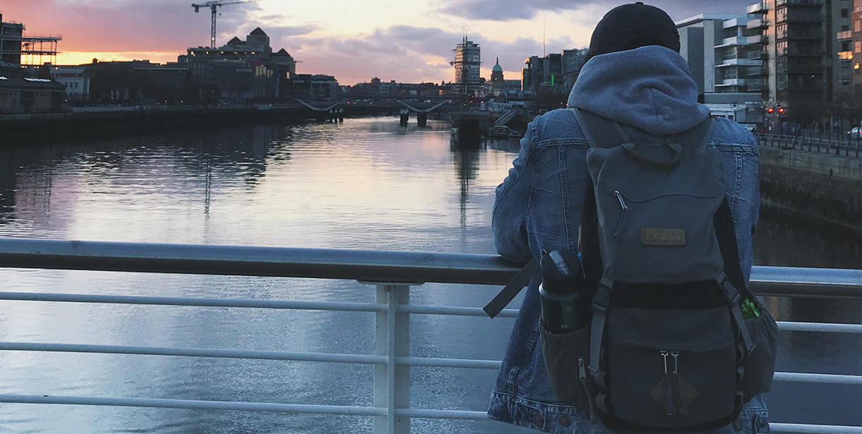 A Study Abroad student stands looking over an Irish cityscape and waterway.