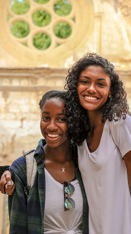 Two UD students hug each other for a photo at an ancient monastery