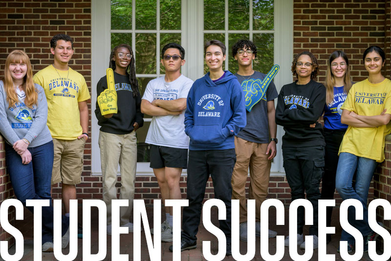 Students wearing University of Delaware gear standing outside of the Center For the Arts.