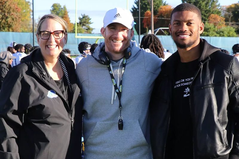 Chrissi Rawak, Director of Athletics, Community, and Campus Recreation, Nassir Adderley, HS19 and Ryan Carty, Head Football Coach