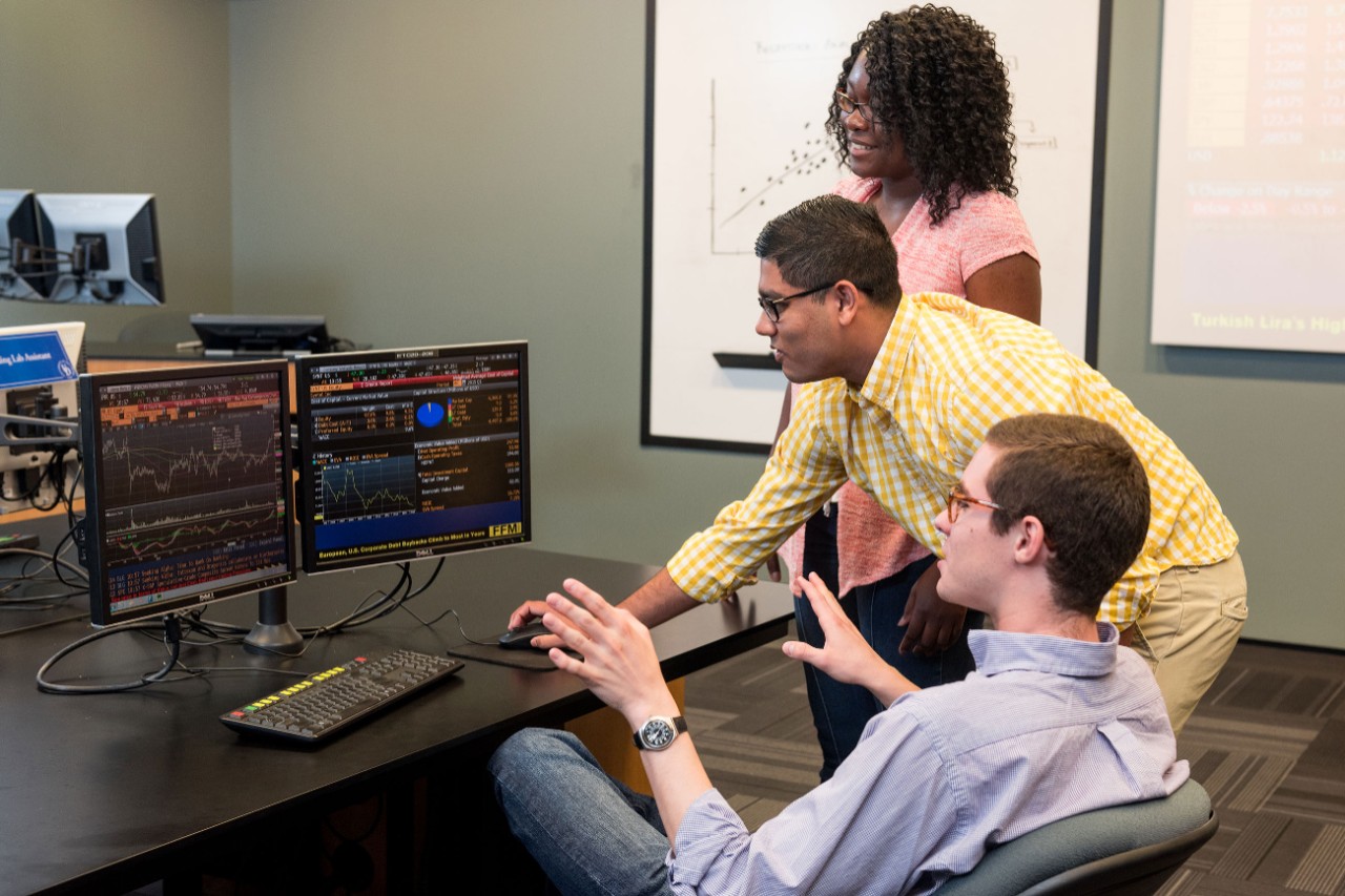 A female and two male UD students work together at a computer. 