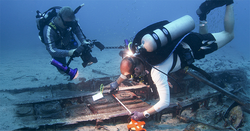UD’s Mark Moline feels fortunate to be part of Project Recover’s effort to bring comfort and closure to families of missing crew members. Here, Scripps Institution of Oceanography’s Drew Pietruszka (right) measures the wing of a P-39 aircraft while Moline photographs the work. UD’s Mark Moline feels fortunate to be part of Project Recover’s effort to bring comfort and closure to families of missing crew members. Here, Scripps Institution of Oceanography’s Drew Pietruszka (right) measures the wing of a P-39 aircraft while Moline photographs the work.