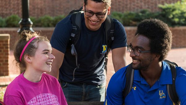 Three students sit together and smile. 