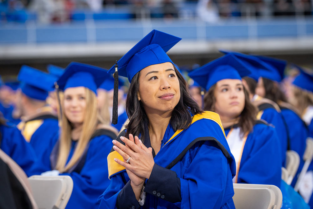 Image of UD graduates sitting at commencement in blue robes. 