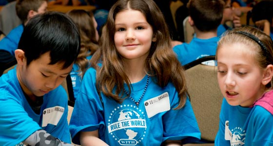 Three young students in blue shirts play together. 