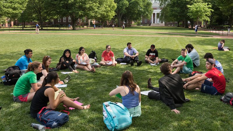 a circle of UD students sitting outside on the green