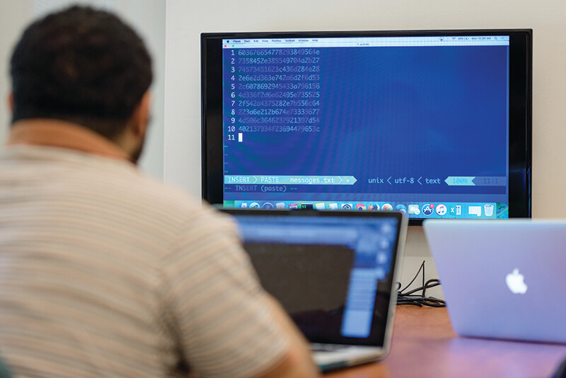 Student works on a laptop in a cryptography class.