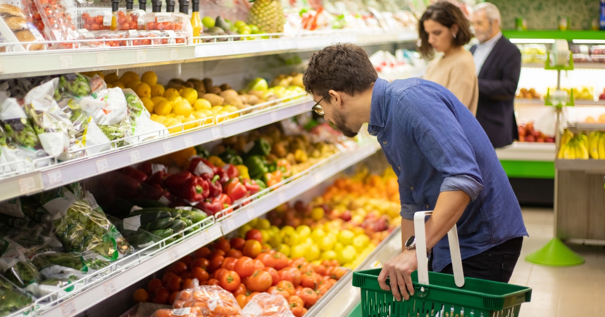 People shopping at a grocery store, comparing prices.