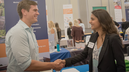Connect with Employers and Alumni Photo of student shaking hands with representative at career fair