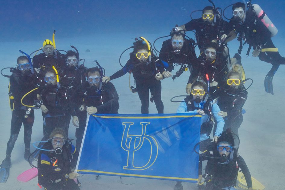 Scuba Diving Students Hold UD Flag
